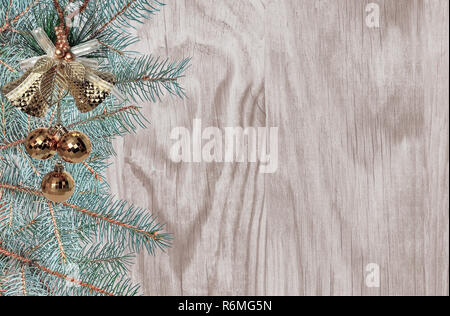 Christmas and New year festive background with green fir tree branches, golden Christmas bells, balls, snowflake and ribbon on wooden surface with spa Stock Photo