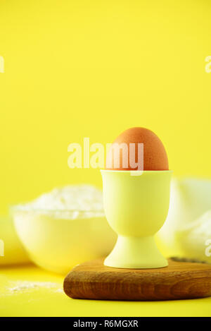 Bakery food frame, cooking concept. Different baking ingredients - butter, sugar, flour, milk, eggs, oil, spoon, rolling pin, brush, whisk over yellow Stock Photo
