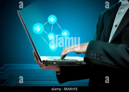 Businessman holding laptop with money network Stock Photo