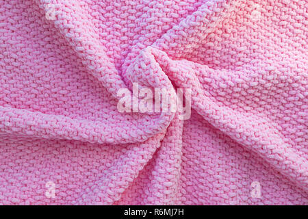 Bright pink knitted plaid made of soft plush yarn. Woolen fabric texture. Handmade craft. Hobby theme. Image for background. Stock Photo