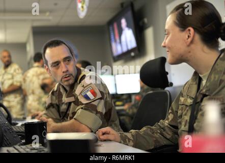 A member of the French air force speaks with a U.S. Airman in the Combined Air Operation Center May 27, 2017, at Al Udeid Air Base, Qatar. The Coalition Forces in the CAOC are responsible for command and control of air power within the Central Command area of responsibility. Stock Photo