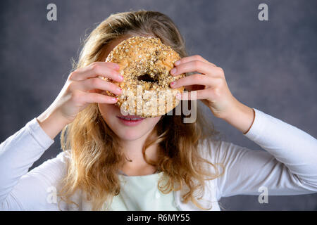 blond girl looking through a big bagel Stock Photo