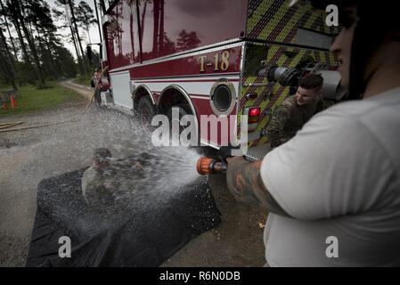 Senior Airman Frank Boniello, 23d Civil Engineer Squadron firefighter performs an initial decontamination of Senior Airman Jonah Phillips, 822d Base Defense Squadron fireteam member during a simulated explosives and hazardous material scenario, May 24, 2017, at Moody Air Force Base, Ga. The exercise simulated initial responses from first responders who then contacted other appropriate units after assessing the potential threat while also assisting the simulated victims of hazardous materials. Stock Photo