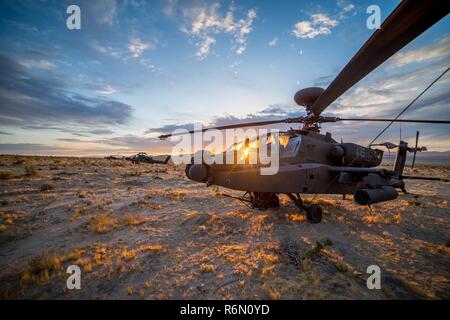 An AH-64 Apache Helicopter from 1st Battalion, 130th Aviation Regiment, North Carolina Army National Guard, sits under a sunset in the Mojave Desert May 30, 2017, at the National Training Center, Fort Irwin, California. (This image was created using high dynamic range techniques) Stock Photo