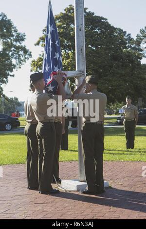 U.S. Marine Corps Lance Cpl. Thomas Rodriguez, Sgt. Jonathon Dorsett, Cpl. Kellen Wonder, and Lance Cpl. Geovanny Romero, prepare to raise the colors during the morning colors ceremony on Camp Lejeune, N.C., June 26, 2017. The Commanders and service members of 2d Marine Division observed the raising of the colors and playing of the service songs to honor military traditions. Stock Photo
