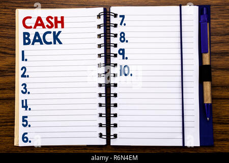 Writing text showing Cash Back Cashback. Business concept for Money Assurance Written on notebook note paper, wooden background with pen and marker. Stock Photo