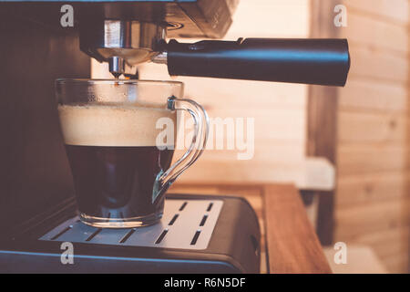 espresso machine pouring strong looking fresh coffee in a  glass cup. strong coffe Stock Photo