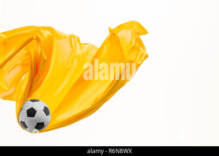 Soccer ball and Smooth elegant transparent yellow cloth isolated or separated on white studio background. Stock Photo