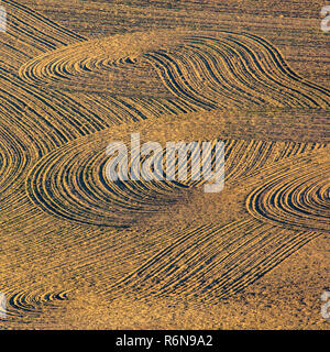 Curving till marks on brown dirt field Stock Photo