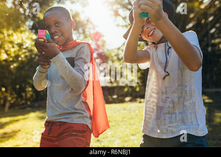 Kids playing with water guns outdoors. Little boys spraying water from a gun in backyard. Stock Photo