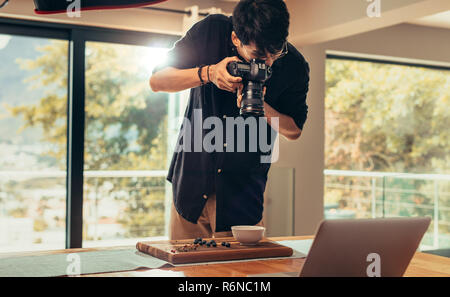 Professional food photographer making shot of food for advert. Male photographer taking pictures of food on wooden board on table with professional ca Stock Photo