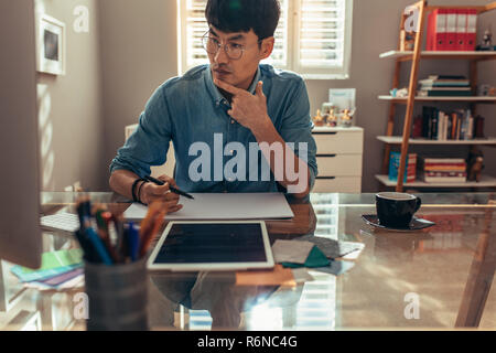 Creative designer working at his office with work tools and accessories on desk. Interior designer working on new project at his workplace. Man sittin Stock Photo