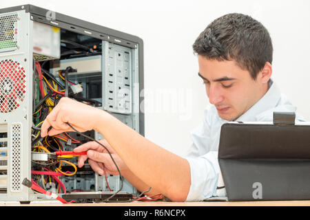 Young technician working on broken computer in office Stock Photo