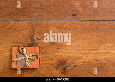 a small package with a heart and a bow on a wooden table Stock Photo