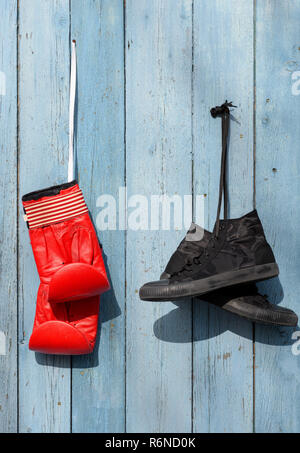 Black textile worn sneakers and red leather boxing gloves Stock Photo