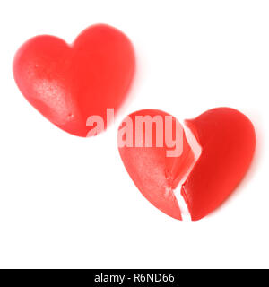 Broken heart or heartache concept with two bright red jelly heart shaped sweets next to each other with one cut in half isolated on white background Stock Photo
