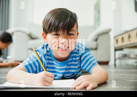 Little Boy Doing his Homework on the Floor Stock Photo