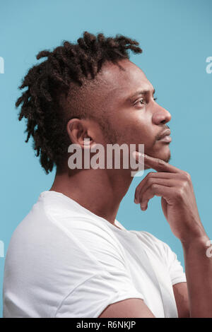 Let me think. Doubtful pensive Afro-American man with thoughtful expression making choice against blue background Stock Photo