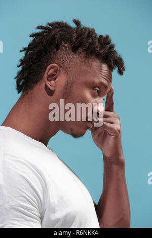 Let me think. Doubtful pensive Afro-American man with thoughtful expression making choice against blue background Stock Photo