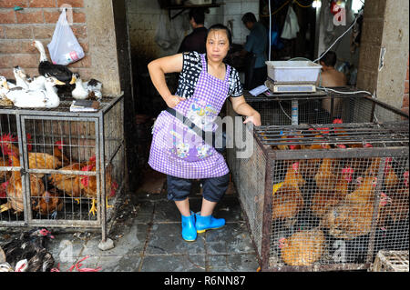 04.08.2012, Chongqing, China, Asia - A female butcher is standing in front of a butcher shop that sells poultry. Stock Photo