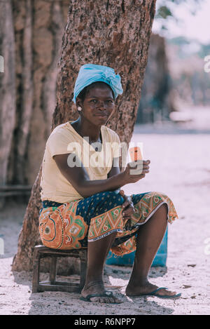 NAMIBIA, MBEYO, MAY 12: An unidentified dirty and poor woman resting in village with cell phone in hand. Kavango region is the highest poverty level i Stock Photo