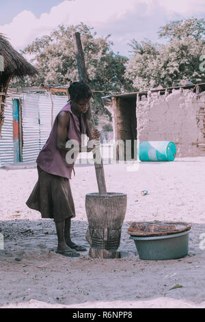 NAMIBIA, MBEYO, MAY 12: An unidentified dirty and poor woman crushing the millet in mortar near town Rundu. Kavango region is the highest poverty leve Stock Photo