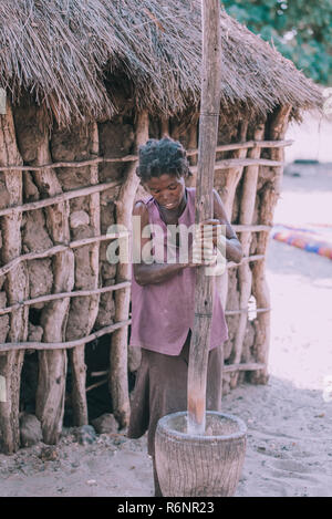 NAMIBIA, MBEYO, MAY 12: An unidentified dirty and poor woman crushing the millet in mortar near town Rundu. Kavango region is the highest poverty leve Stock Photo