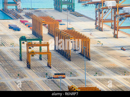 Industrial equipment, freight cranes and steel constructions on pier at empty cargo shipping port of Singapore, aerial view Stock Photo