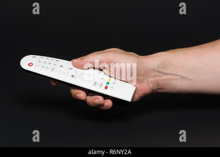 Hand with stylish white remote, isolated on black background Stock Photo
