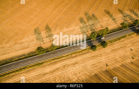 Aerial view of a country road amid fields with a car on it Stock Photo
