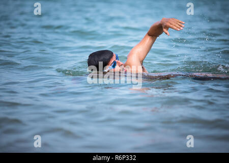 Triathlete man swimming freestyle crawl in ocean - Male triathlon swimmer training for a triathlon Stock Photo