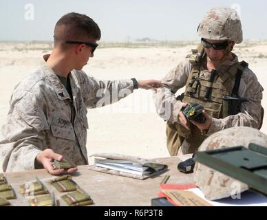 U.S. Marine Corps Cpl. Reagan Schmidt, an ammunition technician with Marine Wing Support Squadron 372, Special Purpose Marine Air-Ground Task Force-Crisis Response-Central Command, hands pistol ammunition to U.S. Marine Corps Lance Cpl. Joseph Lenhard, a tactical switching operator with MWSS-372, SPMAGTF-CR-CC, during a weapons transition range in the Middle East, May 28, 2017. This sustainment range offered an opportunity for the Marines to practice tactical transitions from an M4 carbine to an M9 pistol, ensuring SPMAGTF Marines are prepared to react and respond to a variety of scenarios tha Stock Photo