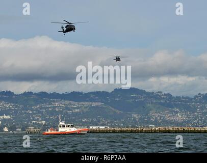 Crewmembers aboard California Air National Guard 129th Rescue Wing HH-60G Pave Hawk helicopters fly over a Coast Guard Station San Francisco 45-foot Response Boat - Medium during a joint training exercise on the San Francisco Bay, April 25, 2017. Members from the Maritime Safety and Security Team 91109, based in San Diego, conducted fast-rope exercises from the HH-60G Pave Hawk helicopters during a interagency training exercise.  U.S. Coast Guard Stock Photo