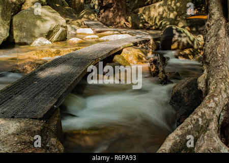 Walkway across a creek flowing through rocks at Jourama Falls, Ingham, Qld AU Stock Photo