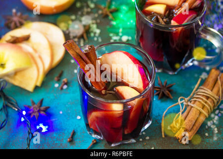 Christmas Mulled Wine or Sangria with Spices close-up. Two glasses of hot mulled wine with Apple and spices on blue slate table. Stock Photo