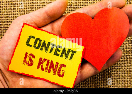 Handwriting text showing Content Is King. Business concept for Online Marketing Information Management With cms Or Seo Data written on Sticky Note Paper With Heart Holding Hand with Finger. Stock Photo