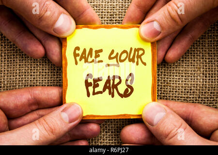 Conceptual hand writing showing Face Your Fears. Business photo showcasing Challenge Fear Fourage Confidence Brave Bravery written on Sticky Note Paper Holding Hand with Finger. Stock Photo