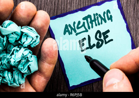 Announcement text showing Anything Else. Business concept for Ask Asking Question to Have Answer written on Notebook Book Man Writing Holding Pen wooden background. Stock Photo