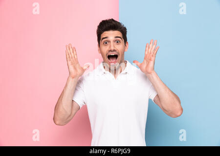 Image of excited man 30s having stubble screaming and raising arms isolated over colorful background Stock Photo