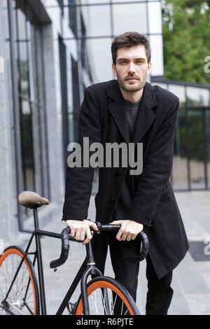 Image of handsome young business man walking outdoors with bicycle. Stock Photo