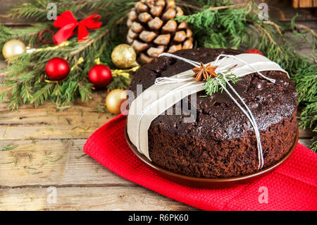 Chocolate Christmas Pudding served on plate with xmas decorations. Wooden background. Stock Photo