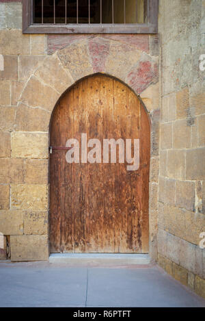 Old wooden door framed by arched bricks stone wall at the courtyard of al Razzaz historic house, Darb al Ahmar district, Old Cairo, Egypt Stock Photo