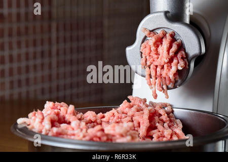 Minced meat coming out from modern electric grinder. Healthy fresh homemade minced meat. Place for copyspace. Stock Photo