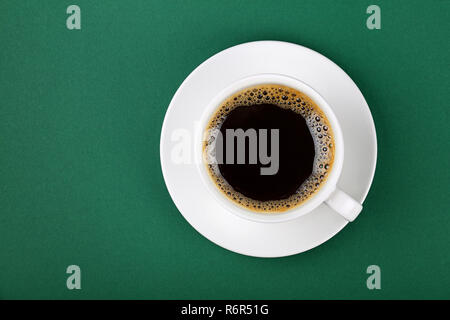 White cup of black coffee on saucer over green Stock Photo