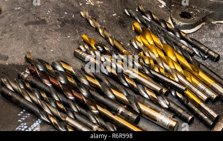 Assorted used drill bits laying on a steel table Stock Photo