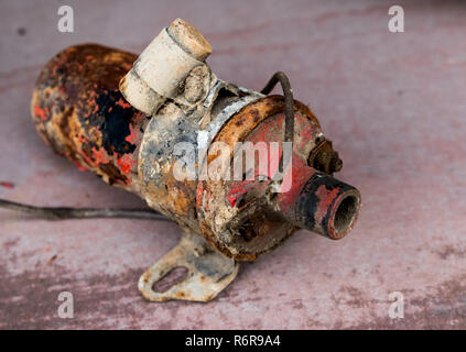 Vintage antique automotive ignition coil with bracket and suppression condenser with rust and peeling paint Stock Photo