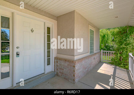 Home with white front door and sunlit porch Stock Photo