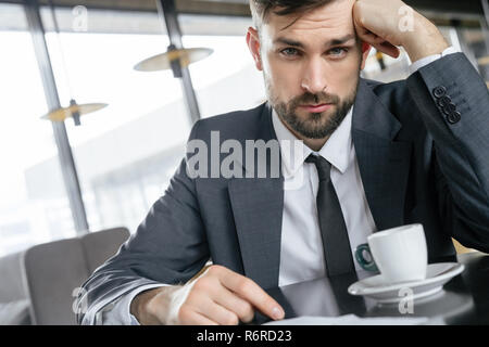 Businessperson on business lunch at restaurant sitting drinking coffee looking camera concerned Stock Photo