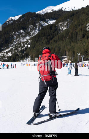 Man skiing in the snow in winter. Young man dressed in red black skiing gear. Skies at Bunderishka polyana, skiers on ski slopes, mountain with pine t Stock Photo