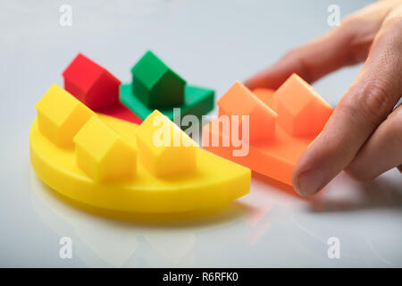 Businessperson Placing A Last Orange Piece Into Pie Chart Stock Photo
